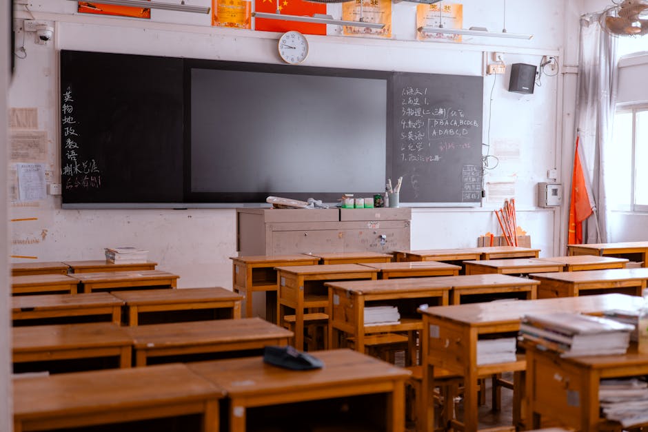An empty classroom with wooden desks and a blackboard, featuring educational materials