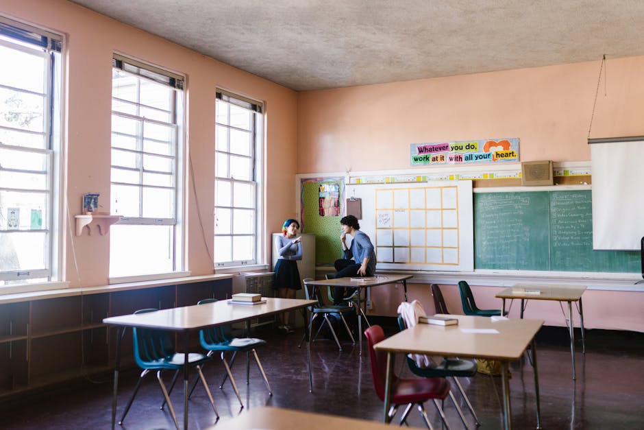 Two students having a conversation in a quiet classroom setting, surrounded by learning materials.