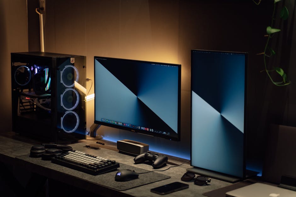 Modern dual monitor PC setup with tech gadgets on a sleek desk in a dimly lit room