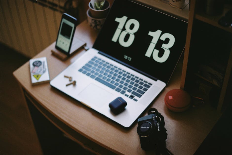 A cozy home workspace with a laptop, smartphone, camera, and headphones